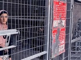A woman wearing hijab behind bars